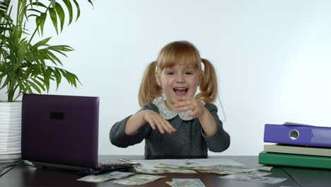 young child girl boss holds a lot of money, rejoices in the win and makes money rain scatters money