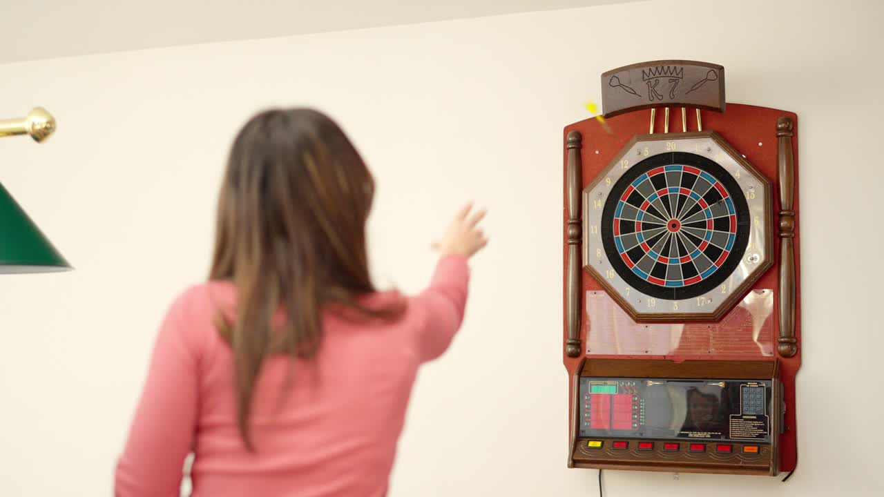 Rear view of a woman playing darts at home