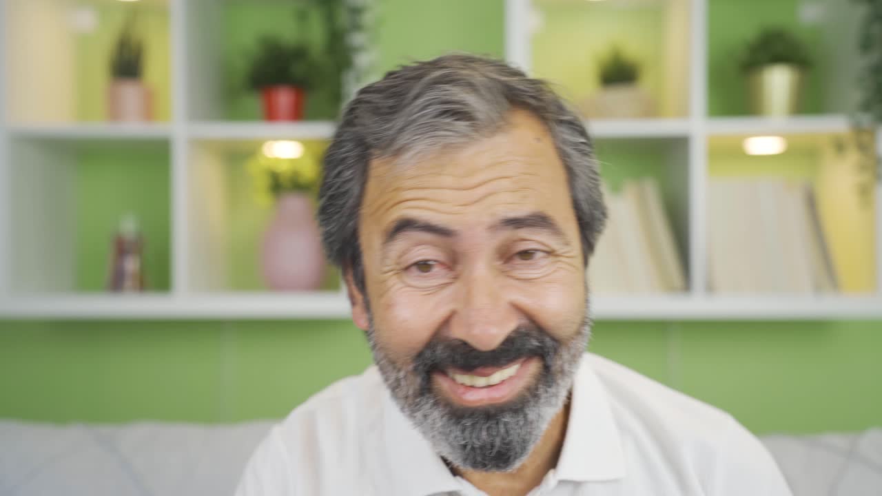 hombre maduro bailando y divirtiéndose mientras mira la cámara en casa.