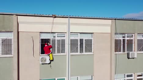 Santa-Claus-entering-a-window-of-a-hospital-hanging-from-a-rope