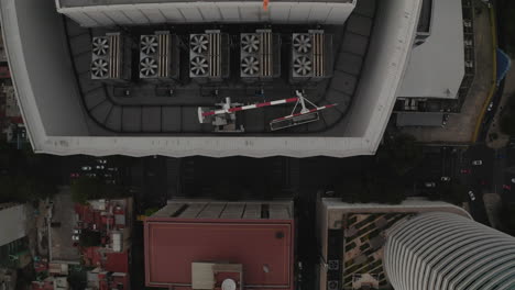 Aerial-birds-eye-overhead-top-down-panning-view-of-tall-office-building-with-heliport-on-roof.-Fly-over-top-of-skyscraper.-Mexico-City,-Mexico.