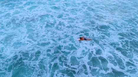 drone aerial footage of a lone surfer paddling out on his surfboard during a golden sunset in weligama, sri lanka.