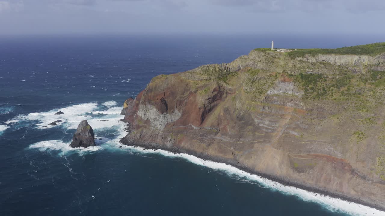 кадры, снятые с беспилотника, на которых волны разбиваются о драматические скалы с маяком над атлантическим океаном на острове сан-жоржи, азорские острова, португалия