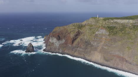 Drohnenaufnahmen-Von-Wellen,-Die-Auf-Dramatische-Klippen-Krachen,-Die-Von-Einem-Leuchtturm-über-Dem-Atlantik-Auf-Der-Insel-Sao-Jorge,-Azoren,-Portugal,-Gekrönt-Werden