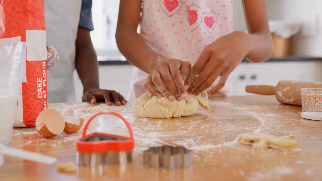Mid section of black girl kneading dough on worktop in kitchen of comfortable home 4k