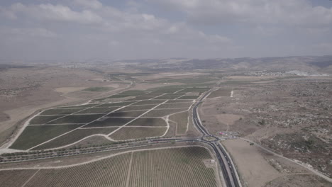 beautiful aerial shot of a valley with agricultural fields and vineyards between mountains and cities in the background(D-LOG)