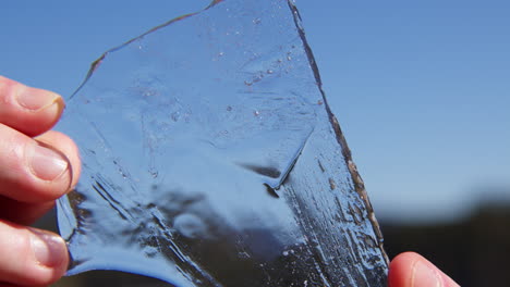 human hand holding clear ice shard. close up shot