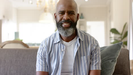 african american middle-aged man with beard smiling while sitting on a couch