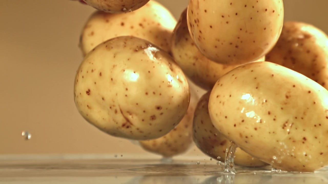Patate fresche che cadono e schizzano acqua al rallentatore