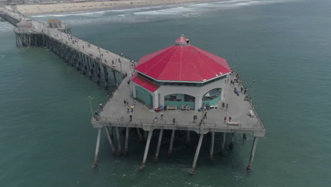 aerial - rotating drone shot of red building at end of ocean pier