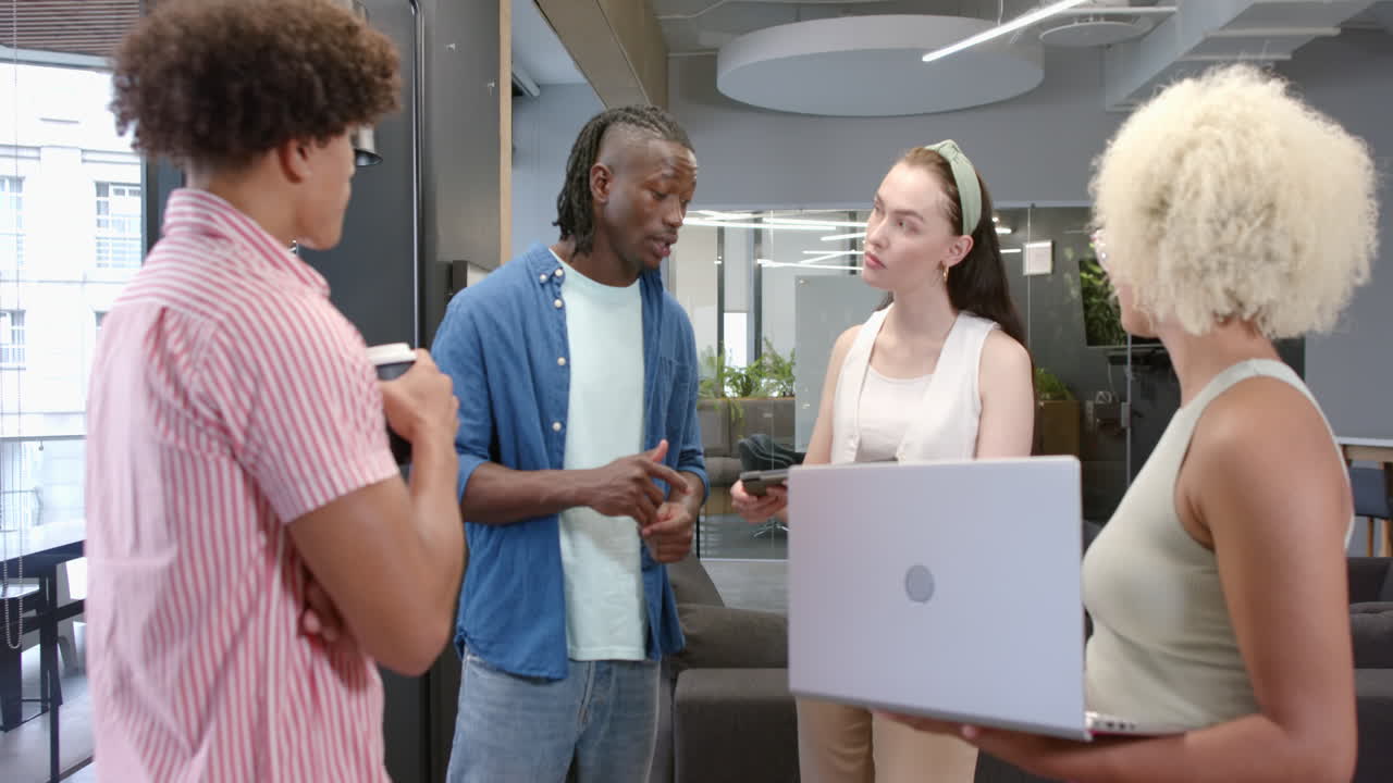 Discussing project, diverse colleagues collaborating with laptop and coffee in office