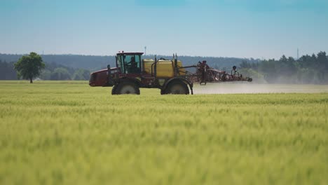 Ein-Traktor-Versprüht-Chemikalien-über-üppige-Weizenfelder