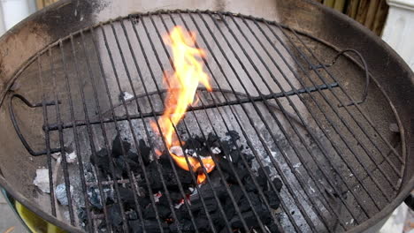 flames shoot up from burning charcoal on a steel bbq