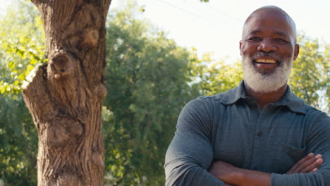 portrait of smiling senior man standing outdoors in garden park or countryside