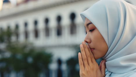 young muslim woman in hijab praying or contemplating outdoors