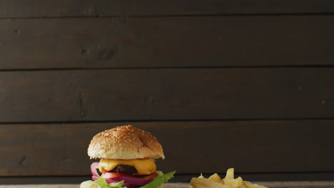 video of cheeseburger and chips against rustic wooden background with copy space