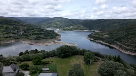 aerial drone footage of house near a river valley in a mountain landscape