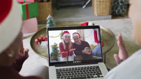 Diverse-senior-female-friends-using-laptop-for-christmas-video-call-with-happy-couple-on-screen