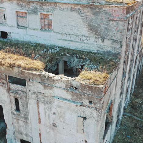 front side of abandoned building exterior without doors and windows. ruined plant after military actions. aerial view.