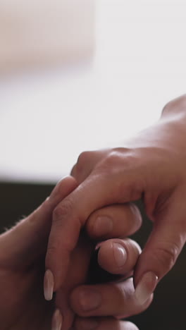 CU shot, slow motion: young couple of man and woman joins hands showing love and relationship on blurred black and white background extreme close view
