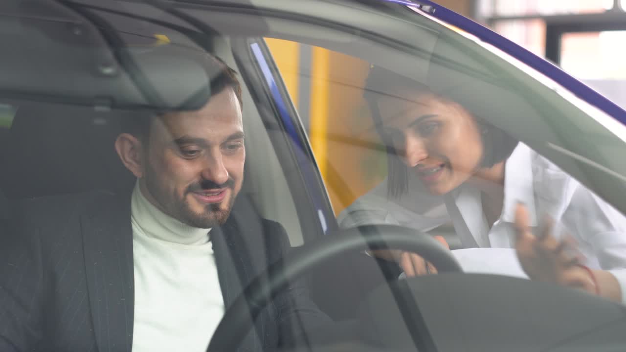 hombre exitoso sentado en el salón de automóviles y hablando con una mujer concesionaria de automóviles. joven hombre confiado eligiendo automóvil en la sala de exposiciones