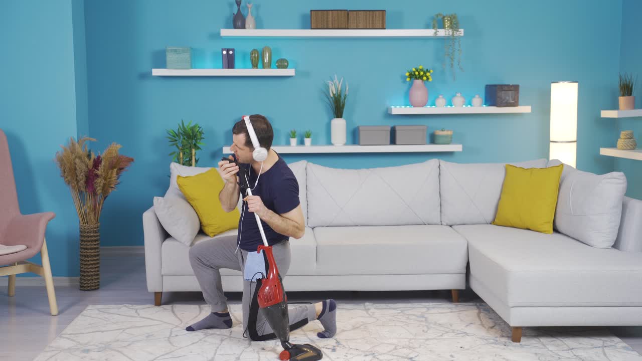 el hombre que limpia su casa se sumerge en la música y de repente se imagina a sí mismo como un cantante con una escoba en la mano.