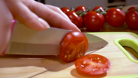 el cuchillo corta el tomate en una tabla de madera en cámara lenta con un disparo de seguimiento de rotación.