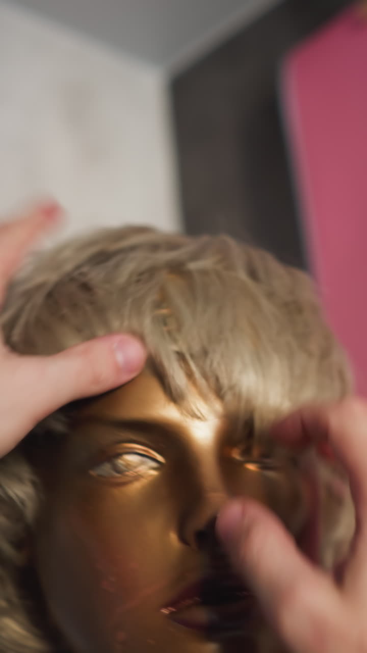 금색 인형 머리의 헤어 스타일을 조정하는 사람의 pov, 흐릿한 배경으로 지원하는 터치를 부여합니다.