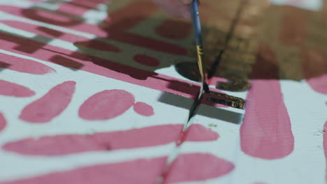 close up of an artist painting in over the letters on a piece of wood