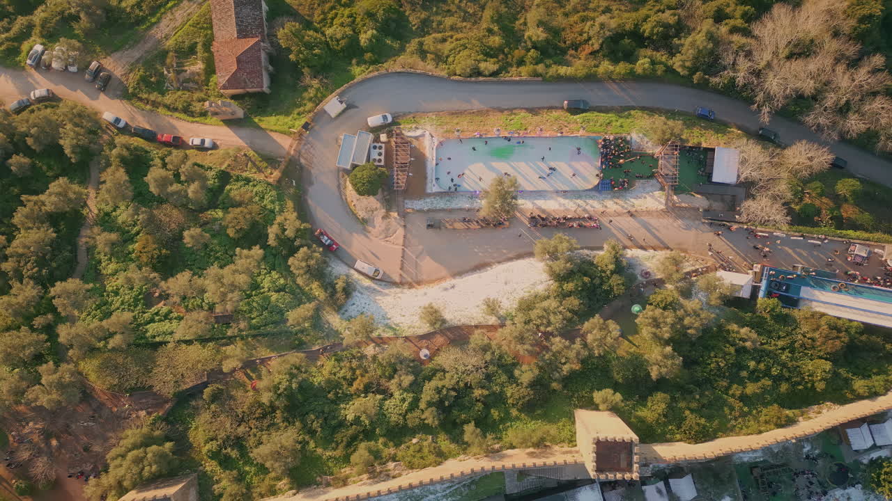 Aerial view village park with ice rink and festive event surrounded greenery.