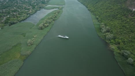 smooth-removal-from-the-boat,-which-is-located-in-the-middle-of-the-river,-opening-the-view-of-a-lonely-boat-and-the-village,-which-is-located-next-to-the-Horizon