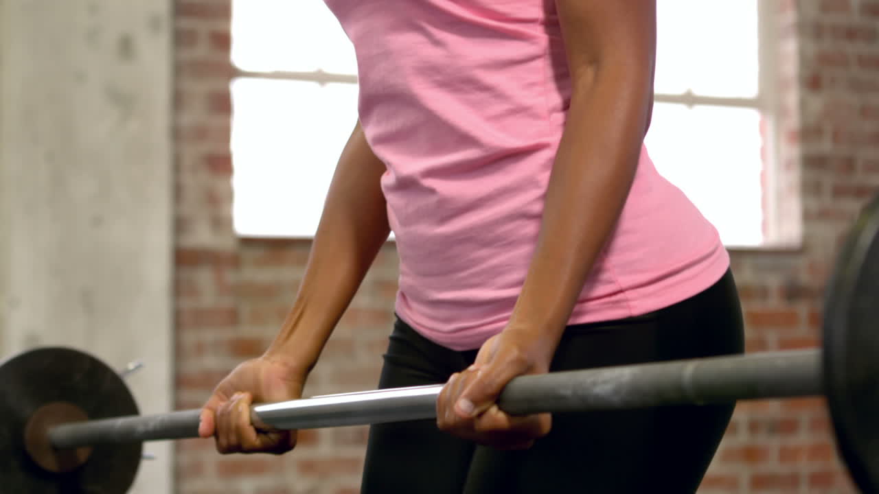 바벨 무게를 들어 올리는 건강한 여성