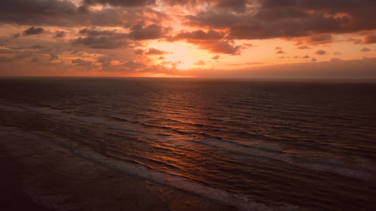 Nedgående droneoptagelse af orange himmel og hav ved solopgang, Itanhaem, Brasilien