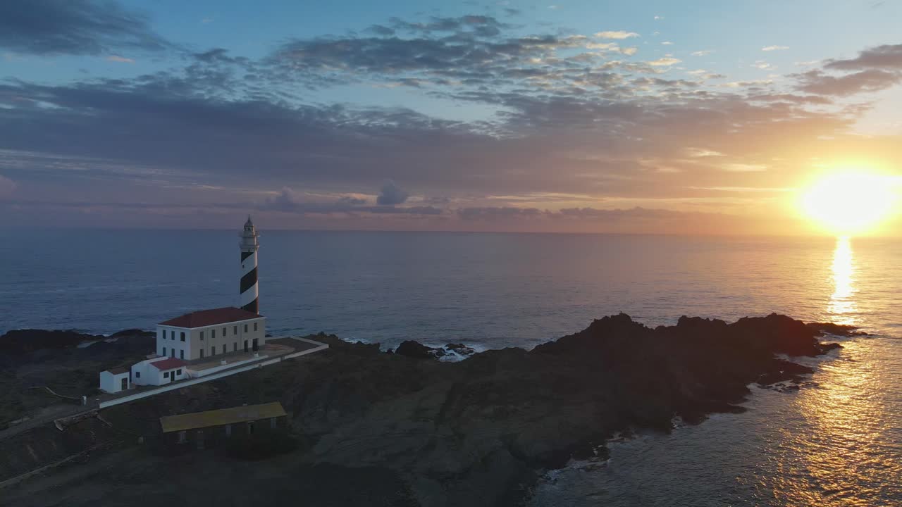 dron cinematográfico panorámico alrededor del faro al atardecer en la cima de un acantilado costero