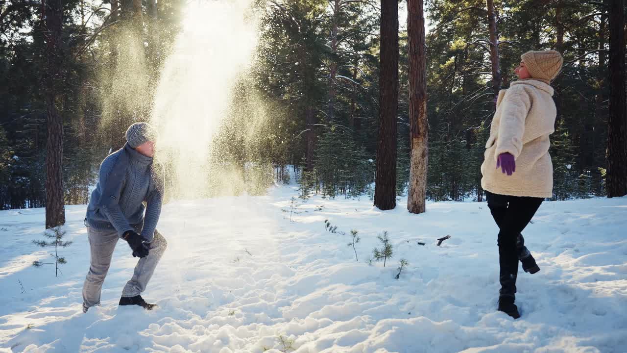 Couple having fun snowball fight in a snowy forest