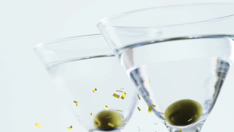 animación de confeti cayendo sobre copas de cóctel con aceitunas sobre fondo blanco