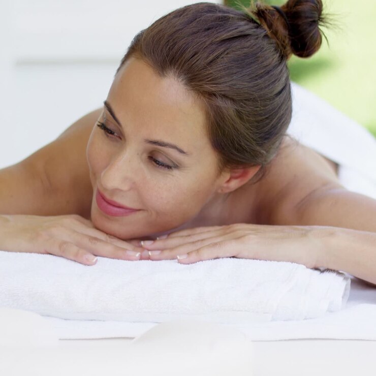 donna curiosa sul tavolo della spa avvolta in asciugamani bianchi