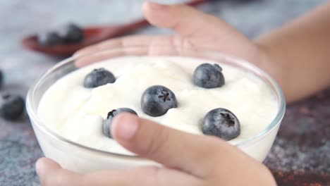 child eating yogurt with blueberries