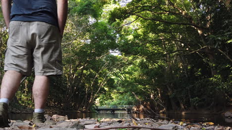 walking in front of camera to the creek edge to enjoy the view