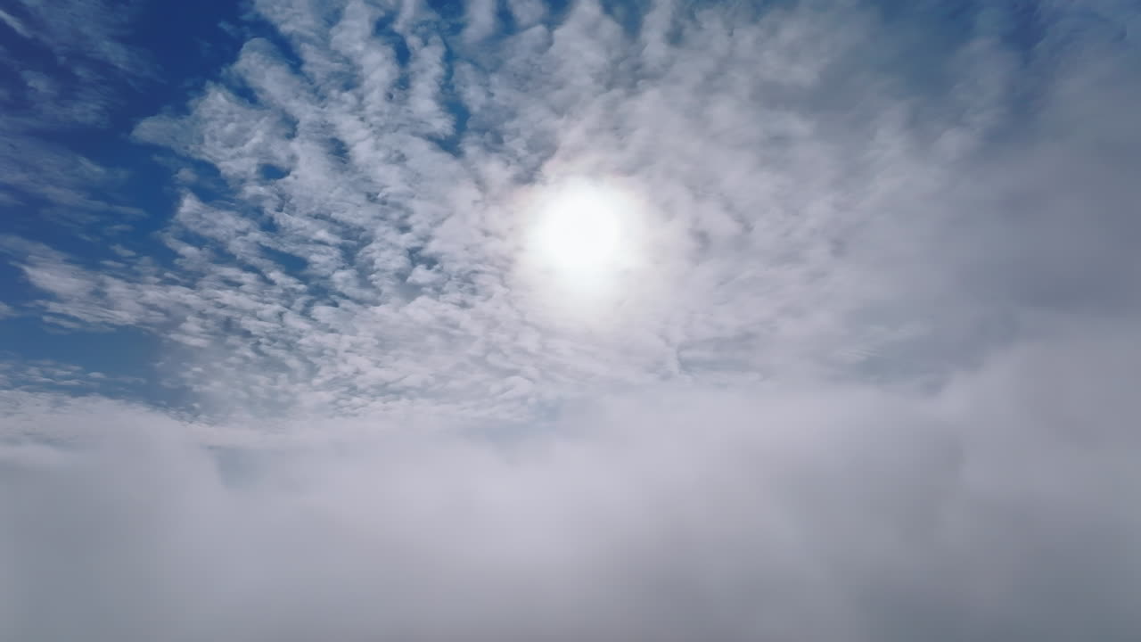 Aerial drone view of the sky with clouds and bright sun