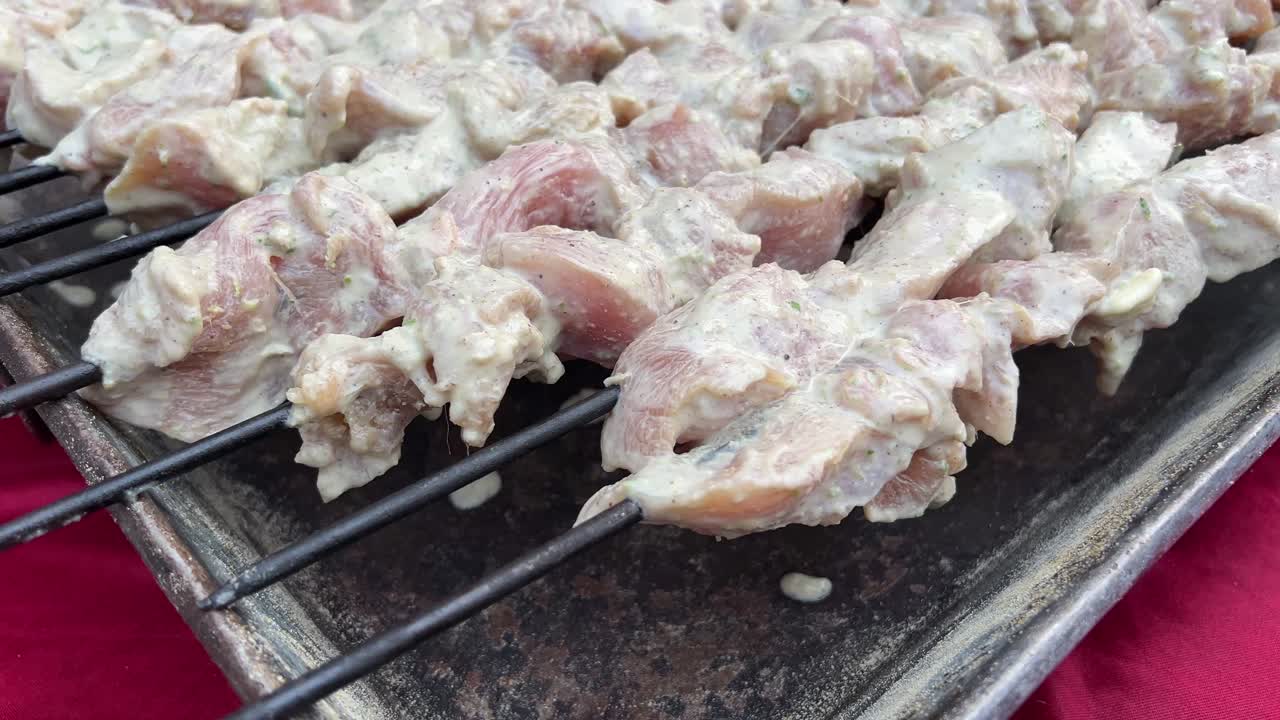 Raw chicken kebab pieces strung in skewers prior to roasting.