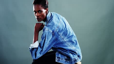 androgynous man in denim shirt posing against colored background