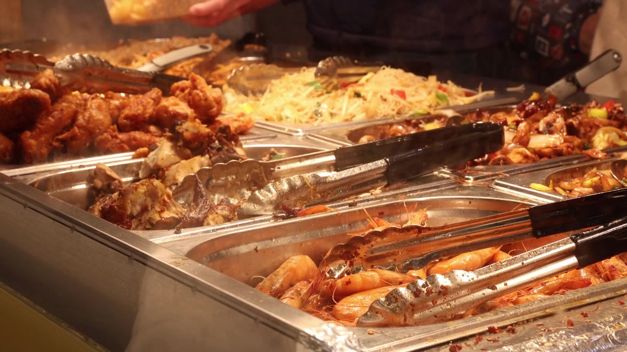 Persone che mettono cibo nei piatti in un ristorante cinese a buffet self-service.