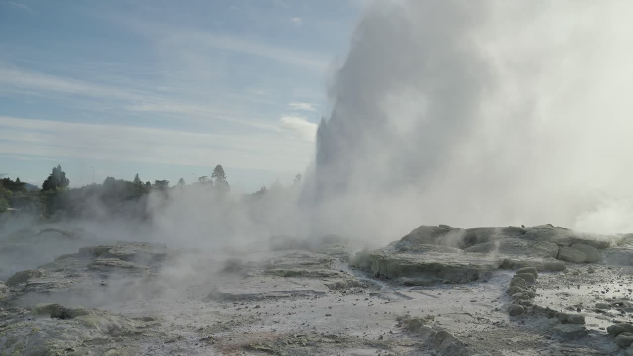 géiser geotérmico en erupción con vapor y agua, rotorua, nueva zelanda, cámara lenta icónico entorno rocoso de vapor, cielo soleado durante el día