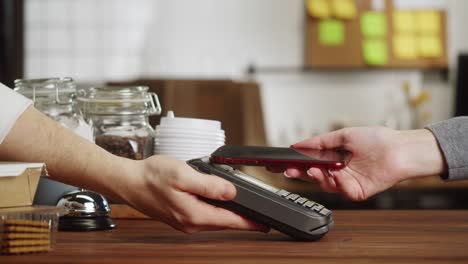 pagar con un primer plano de teléfono inteligente, utilizando la tecnología nfc en un restaurante. el cliente paga por teléfono móvil, tecnología sin contacto, pago sin contacto en un café.