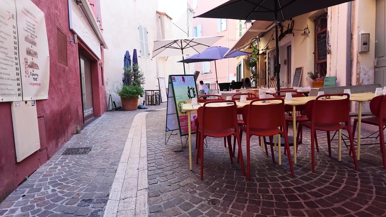 Tavoli vuoti in un ristorante all'aperto su un'incantevole strada europea acciottolata.