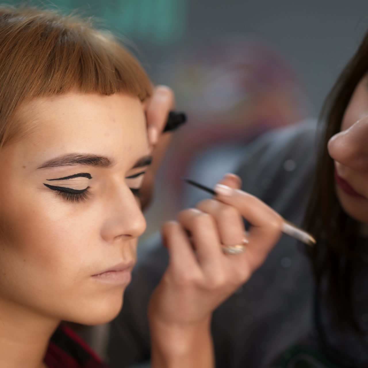 Make-up artist doing makeup. Female portrait. Close-up of hand near face.