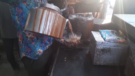 close up of hot indian masala chai being poured into glass cup. indian chai tea