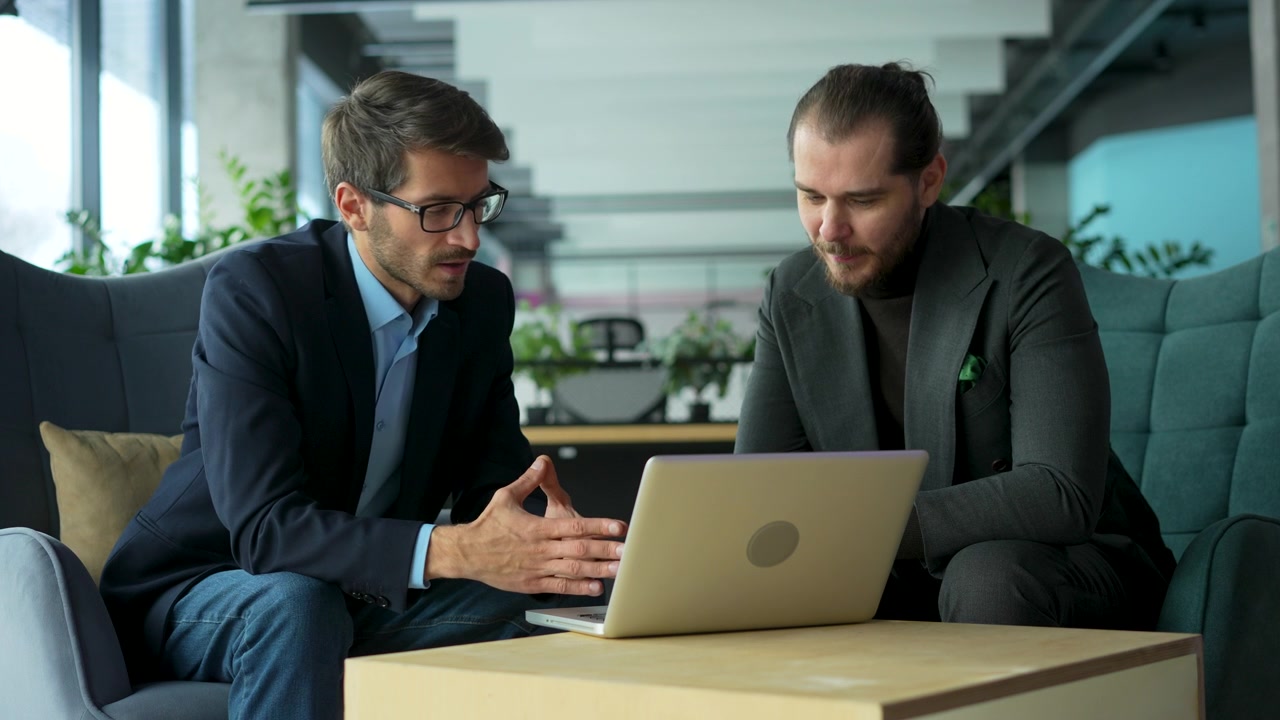 Due professionisti che collaborano su un laptop in un ufficio moderno