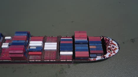 Aerial-side-and-top-view-of-a-large-container-ship-cruising-slowly-along-on-a-sunny-day
